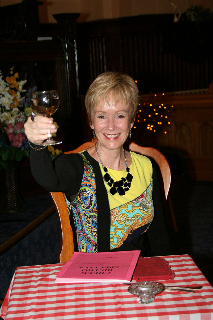 Kerry-Anne Kutz in performance with raised wine glass